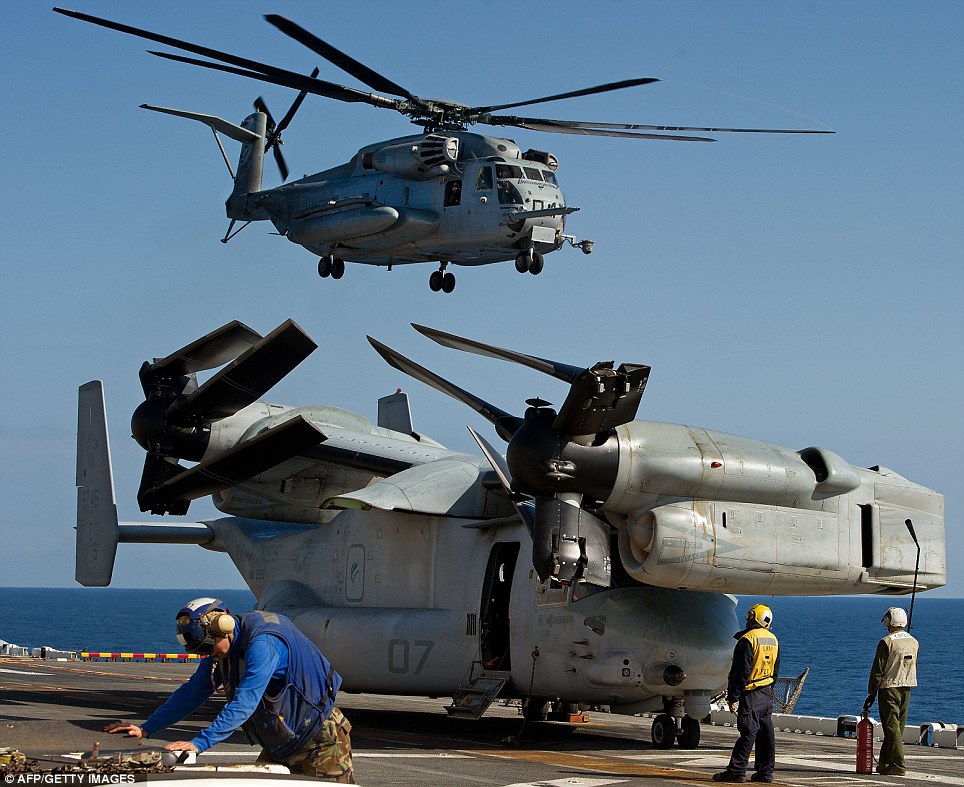 Might: A crew members makes checks as a helicopter takes off carrying Marines